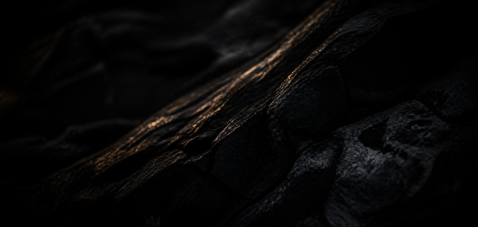 Close-up of dark stone lit by a thin band of warm light